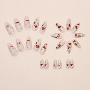 Detailed close-up of almond-shaped press-on nails featuring red roses and gold outlines