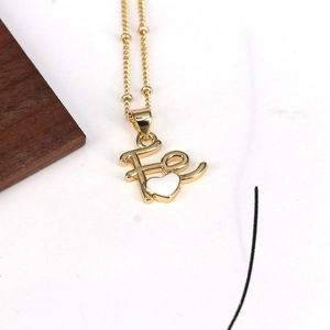 Detail of gold bead chain necklace featuring a white heart charm and Fe letter pendant