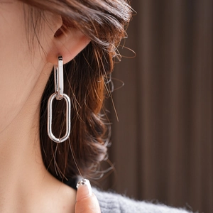 Close-up of silver geometric chain earrings worn on model for a trendy minimalist look