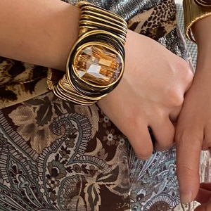 Detail of bohemian gold and black braided cuff bracelet with amber oval gemstone