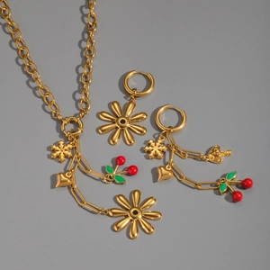 Detail view of 18K gold necklace and earrings set with cherry and floral enamel charms