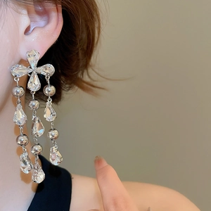 Detailed macro view of silver tassel earrings with crystal water drop pendants on ear