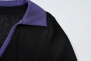 Détail du col à revers violet côtelé et du tricot noir sur un haut à manches longues