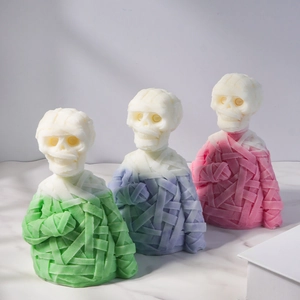 Three mummy skull candles with gauze texture in green, purple, and pink on marble