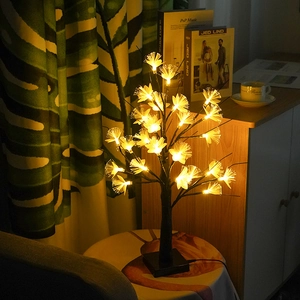 Detailed view of warm white LED birch tree lamp with fiber optic flowers on a wooden stool