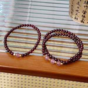 Detailed shot of garnet and strawberry quartz beads with golden metal spacers on a stand