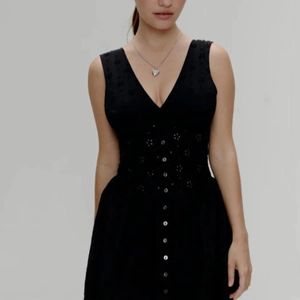 Elegante zwarte mouwloze jurk met V-hals, opengewerkt borduursel en knopen