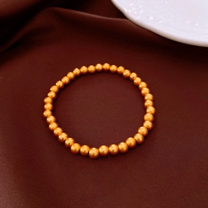 Detailed macro view of 18k gold plated cat eye bead bracelet on dark red fabric