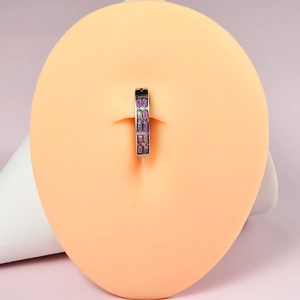 Macro shot of silver stainless steel belly ring with purple opal stones on a model