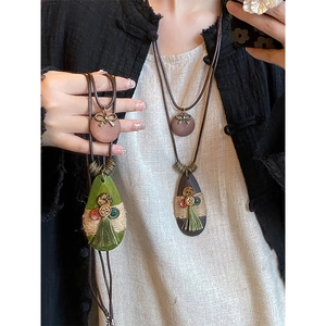 Detail of Bohemian teardrop necklace with bow, buttons, and tassels on a model