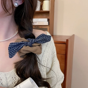 Detail of blue plaid and brown fabric bow scrunchie on braided hair with pearls