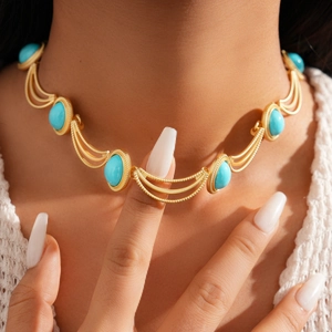 Gros plan d'un collier en chaîne dorée avec gemme ovale turquoise sur un mannequin