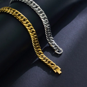 Dettaglio di bracciali a catena cubana oro e argento con finitura lucida su sfondo scuro