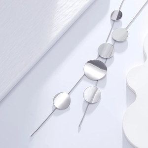 Macro view of minimalist long necklace with polished circular metal pendants and fine snake chain