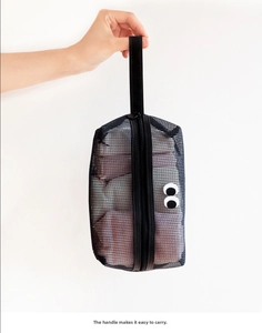 Handheld black mesh organizer bag featuring large white eye patches and a sturdy handle
