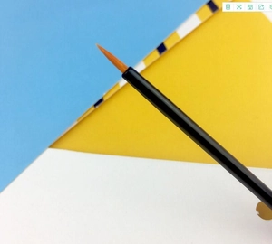Detail of portable eyeliner brush with orange nylon bristles and black handle on colorful background