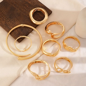 Detail view of seven gold geometric bangles and necklaces with glossy metallic texture