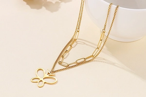 Detail shot of golden double-layer necklace featuring a hollow butterfly pendant charm