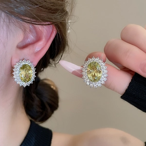 Macro shot of sun-shaped earrings with yellow oval gemstone and silver-toned petals