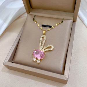Détail du pendentif lapin aux gemmes roses et cristaux dans un écrin beige