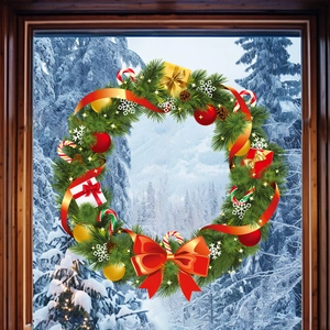 Couronne de Noël avec aiguilles de pin, nœud rouge et ornements devant la fenêtre