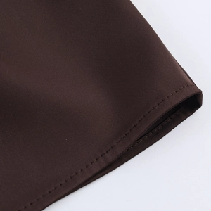 Detail view of smooth dark brown satin fabric with professional hem stitching work