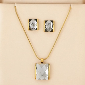 Detail of a gold jewelry set with emerald-cut grey crystals in a soft beige jewelry box