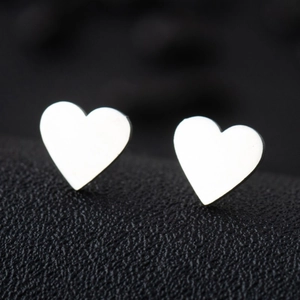 Macro shot of polished silver heart-shaped stainless steel earrings on black leather