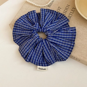 Détail d'un chouchou en tissu écossais bleu avec étiquette faite main sur un livre