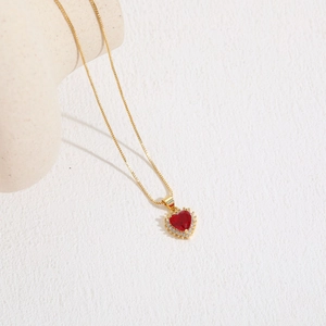 Detail of a 14K gold plated heart necklace with a red zircon and pavé crystal halo