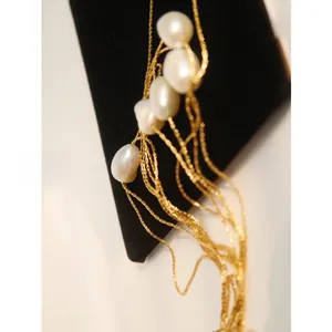 Detailed view of layered gold titanium steel necklaces with baroque pearls on a display
