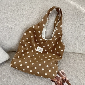 Detailed close-up of brown corduroy tote bag with white polka dots and fabric label