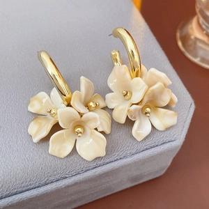 Detail of cream marble resin flower earrings on a light gray jewelry display box
