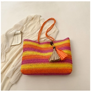 Detail of colorful striped straw tote bag featuring orange handles and wooden bead tassels