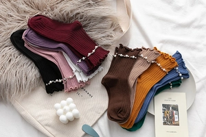 Detail showing ribbed cotton socks with elegant pearl beads and ruffle edges in various colors