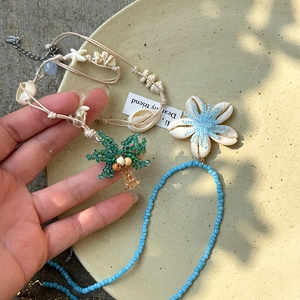 Détail de collier en perles fait main avec breloques de coquillage et cocotier