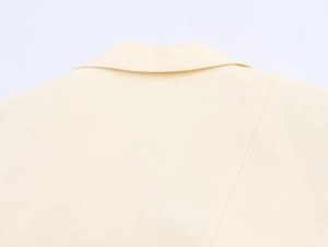 Close-up of the notched lapel and woven texture on this cream longline blazer