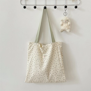 Detail of floral tote bag with embossed texture and green handles in a cozy setting