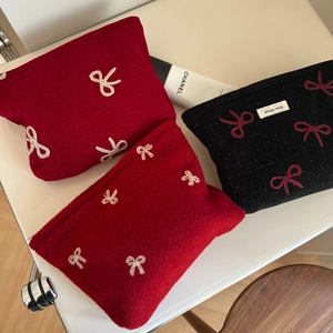 Detailed view of red and black textured cosmetic bags with delicate bow embroidery details