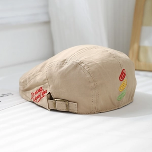 Detail of beige cotton canvas beret with cursive embroidery and metal adjustment buckle