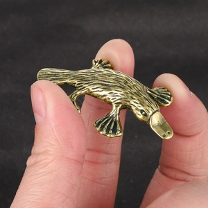 Macro detail of vintage brass platypus figurine showing fur texture and small scale