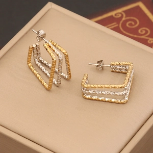 Detail shot of geometric two-tone earrings with diamond-cut texture and layered design