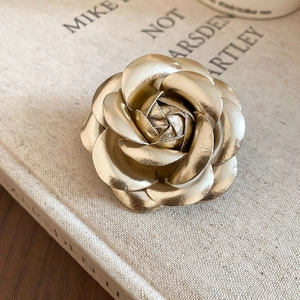 Detail of elegant camellia brooch with golden matte petals on vintage book background