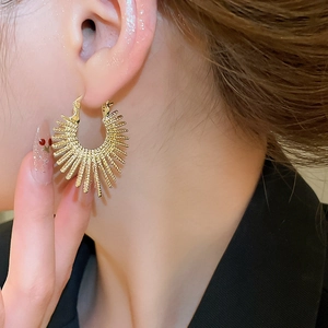 Close-up of a gold sunburst ear cuff featuring a textured radial sunbeam pattern on model