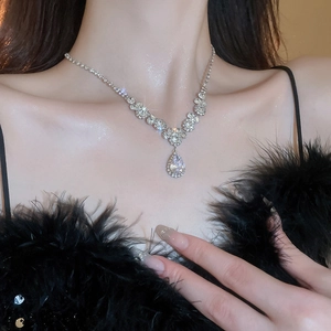 Macro detail of teardrop crystal pendant necklace on a model with sparkling stones