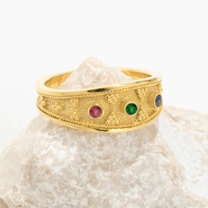 Detailed shot of golden ring with colorful zircons on natural white stone base