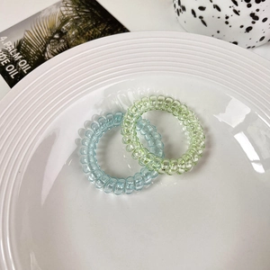 Detail of light blue and light green spiral hair ties on a white decorative plate