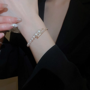 Detail of multilayer pearl open bracelet with pavé diamonds on a stylish suit sleeve