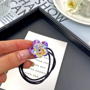 Detailed view of a crystal flower hair tie with purple beads on an elastic black band
