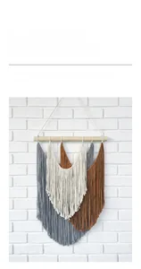 Detail of woven Bohemian tapestry with layered grey and beige tassels on a wood rod